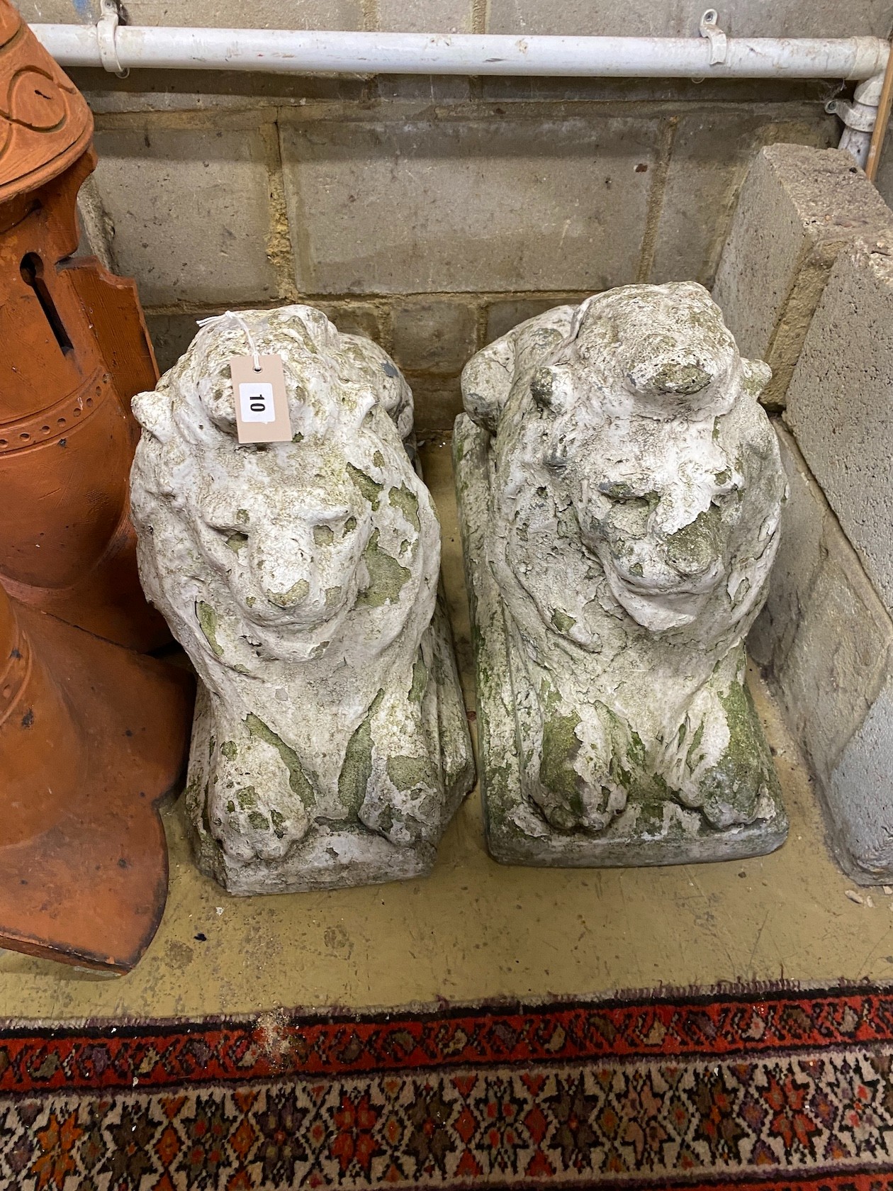 A pair of reconstituted stone recumbent lion garden ornaments, length 70cm, height 50cm, 29cm width